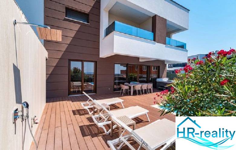 Terrace with loungers at the villa in Novalja with a sea view and a shower.