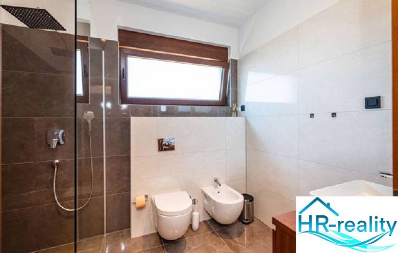Modern bathroom with a large window in the villa, featuring a shower and toilet.