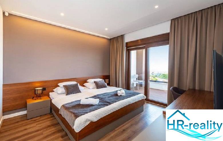 Luxury bedroom in a villa with a balcony, wooden decor flooring, large windows.