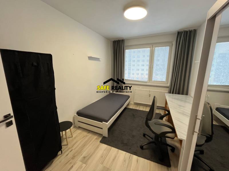 Bedroom in a 3-room apartment with a bed, table, and wooden decor flooring.