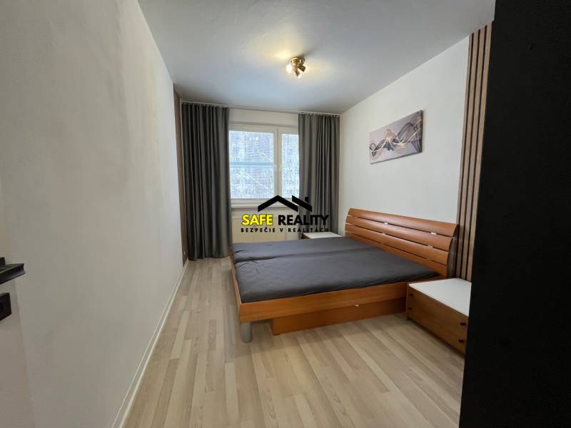 A bedroom with light walls, a double bed, and a floor with a wood decor in a 3-room apartment.