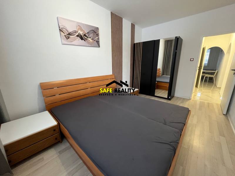 A bedroom in a 3-room apartment with a wooden decor floor, a wardrobe, and a modern painting.