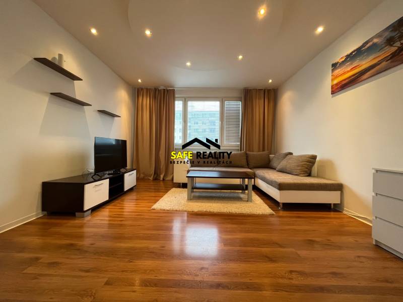 Living room with wood-patterned flooring, a sofa, and a television in a three-room apartment.