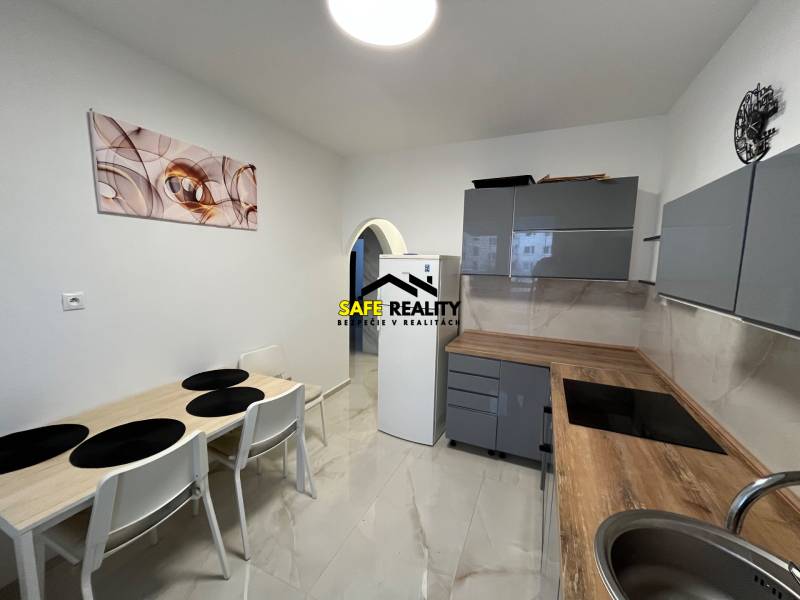 A kitchen in a 3-room apartment with a kitchen unit, table, and wall decoration.