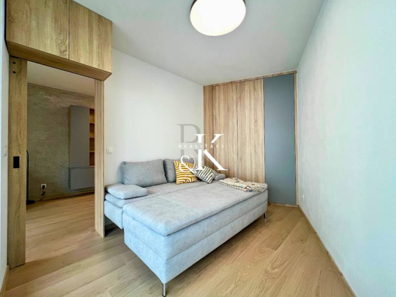 Living room in a two-room apartment with a sofa and a wooden decor floor.