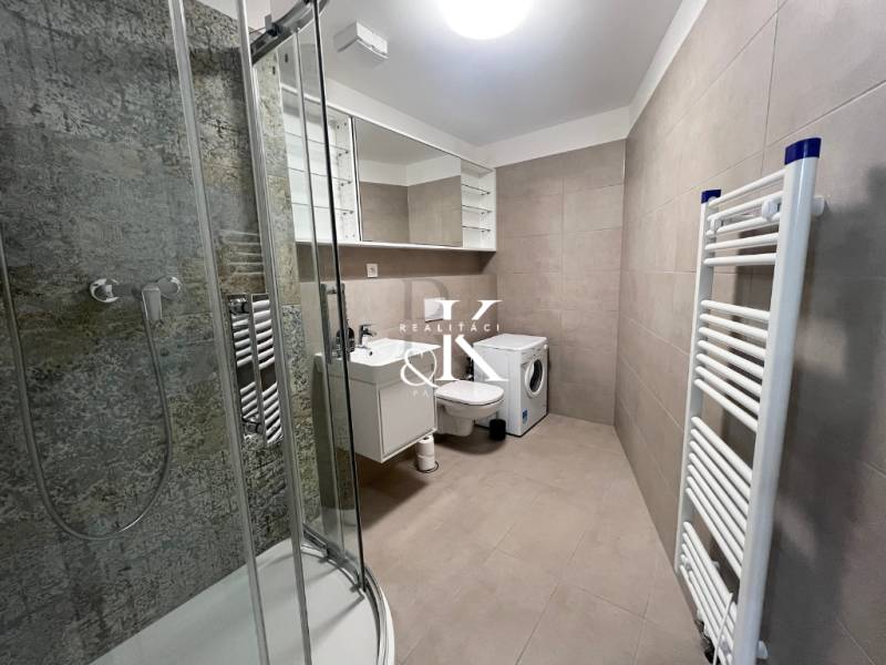 A bathroom in a 2-room apartment with a shower, washing machine, and ladder radiator.