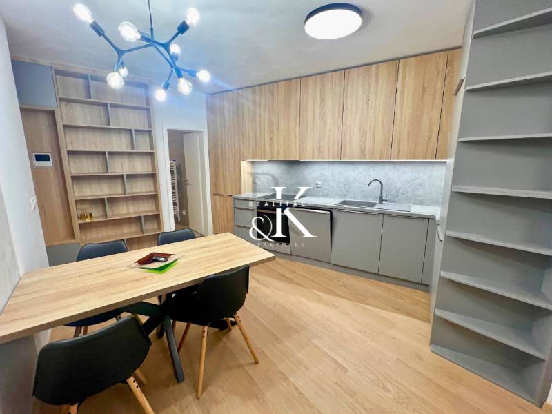 Kitchen and dining room in a 2-room apartment with a wood-patterned floor and shelves.