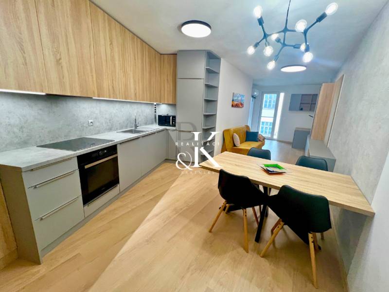 A kitchen in a two-room apartment with a wooden decor floor and a dining table.