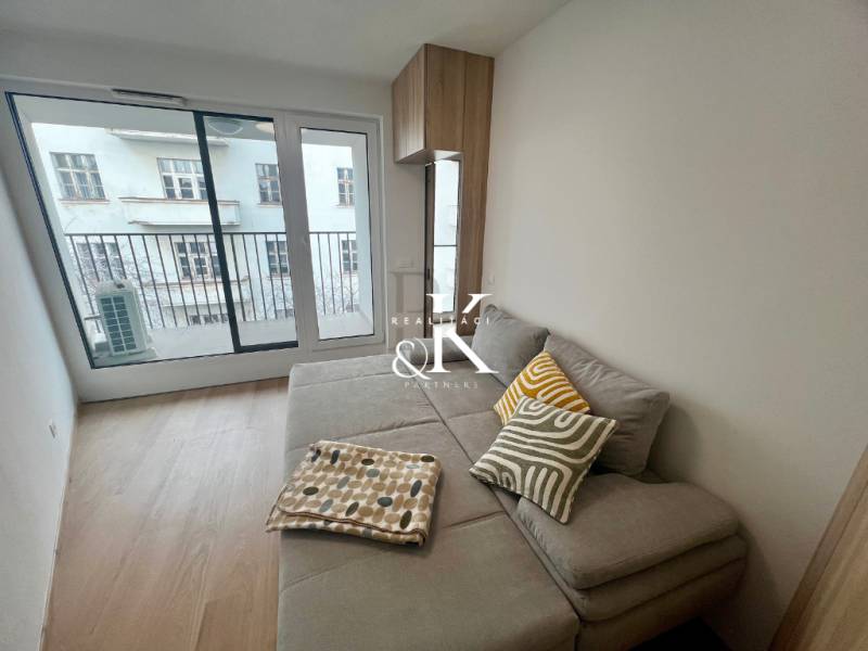 Living room in a two-room apartment with a corner sofa and a balcony, wooden decor flooring.