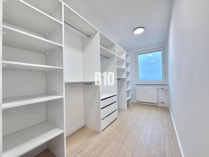 Spacious dressing room with wooden decor flooring in a 3-room apartment.