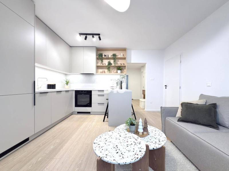 Living room and kitchen in a three-room apartment with a wooden decor floor.