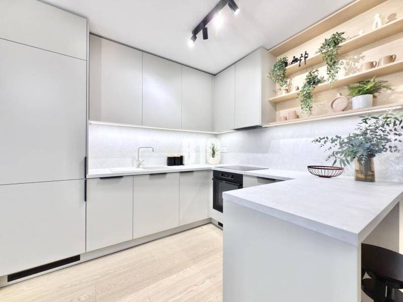 A kitchen in a 3-room apartment with white cabinets and a wood-patterned floor.