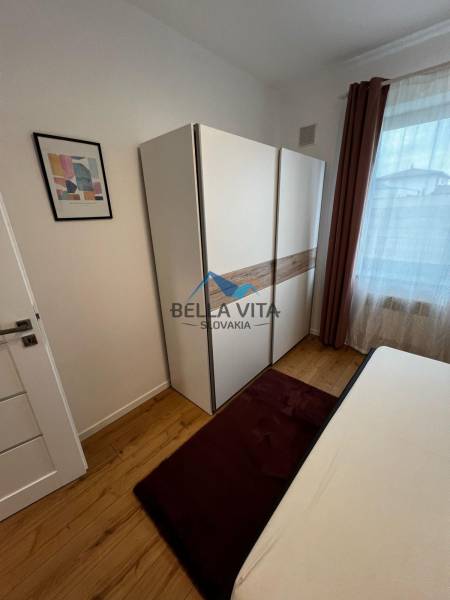 Bedroom in a cozy 2-room apartment on Brečtanová street, light wardrobe, bed, window.