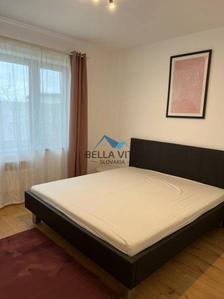 Bedroom on Brečtanová Street in a 2-room apartment with a bed and a painting.