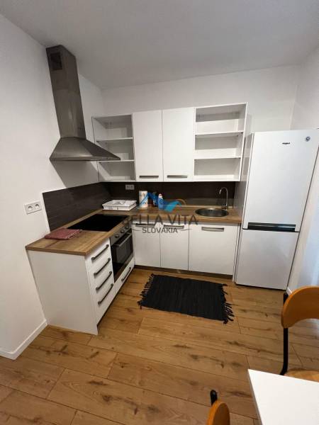 The kitchen in the 2-room apartment on Brečtanová Street with wooden flooring and white furniture.