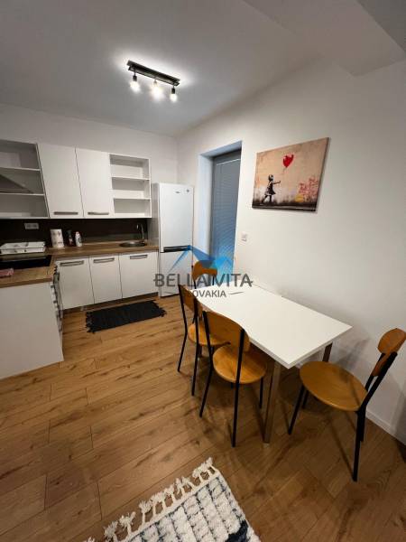 A kitchen with a wooden floor, a white table, and a painting. On Ivy Street, a 2-room apartment.