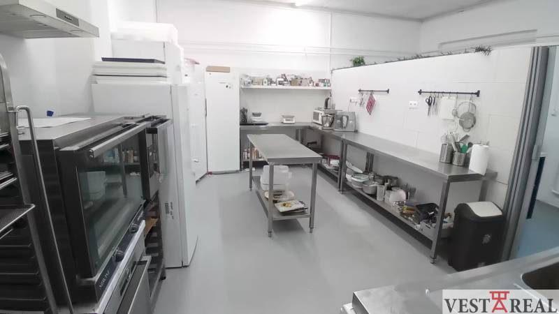 Kitchen equipment in a warehouse hall with stainless steel furniture and appliances.