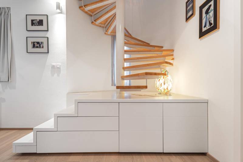 A stylish spiral staircase in a 4-room apartment with a wooden decor floor.
