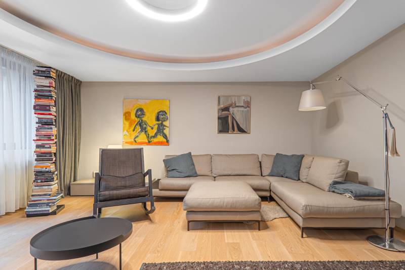 Living room with wood-patterned flooring, a corner sofa, and a bookshelf.