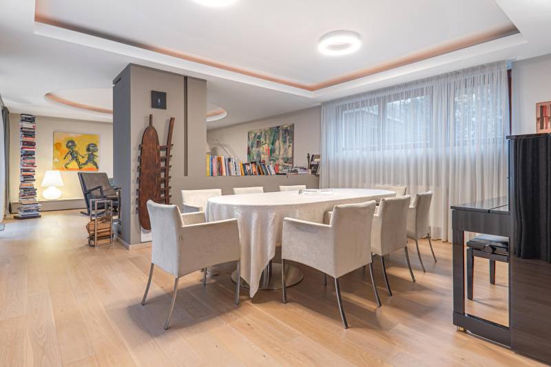 Dining room in a 4-room apartment with wood-patterned flooring, a round table, and art on the walls.