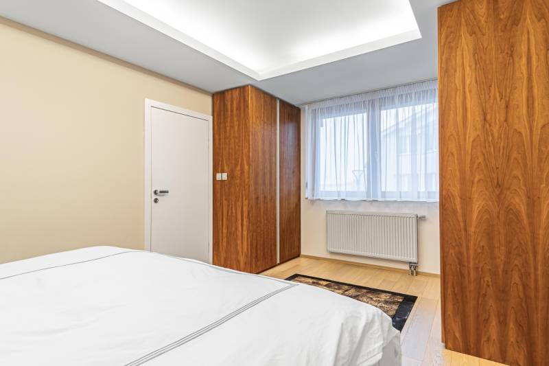 A bedroom with a wood-patterned floor, built-in wardrobe, and a window in a 4-room apartment.
