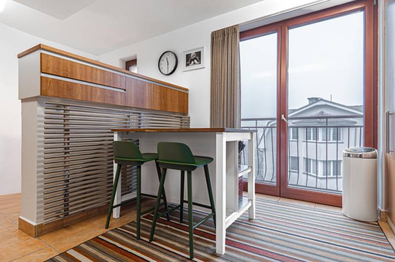 Dining area with chairs in a 4-room apartment with a striped carpet.