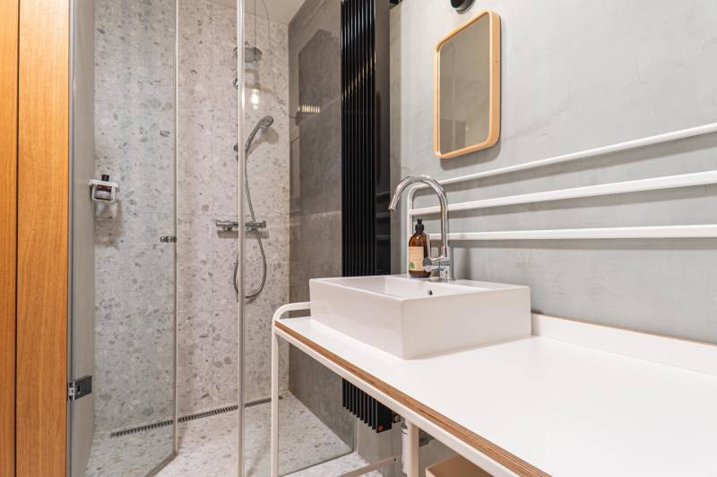 Bathroom with a shower, sink, and tile decor in a four-room apartment.