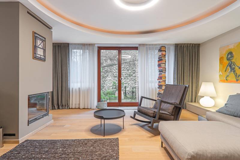 Living room in a 4-room apartment with a wooden decor floor, a fireplace, and a comfortable armchair.