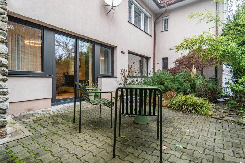 Courtyard of a 4-room apartment with outdoor seating, interlocking paving, and greenery.