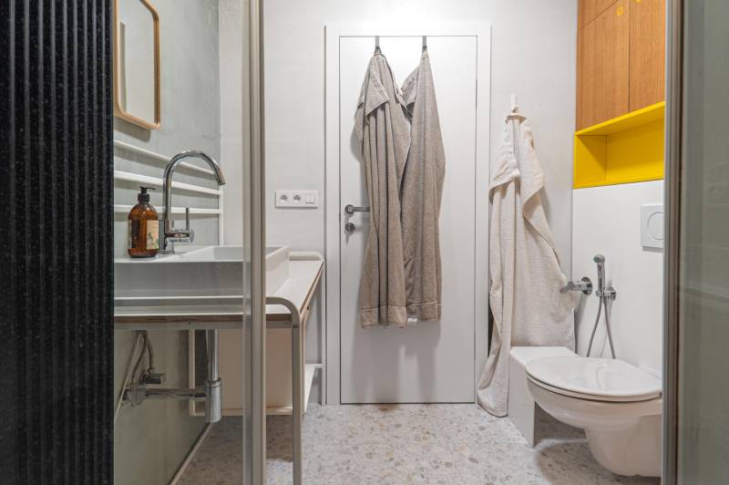 Bathroom with a shower, sink, toilet, and towels in a 4-room apartment.