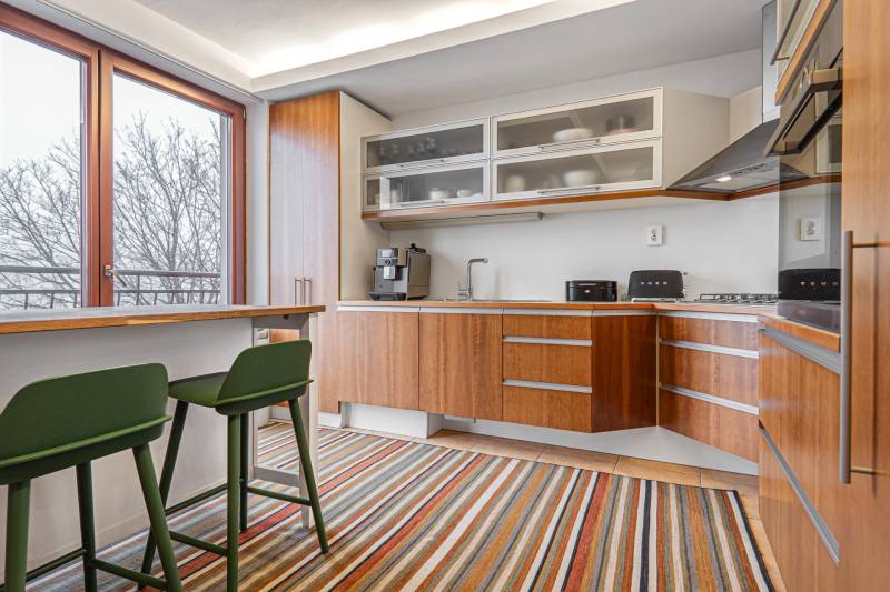 A kitchen in a 4-room apartment with wooden decor, a colorful carpet, and large windows.