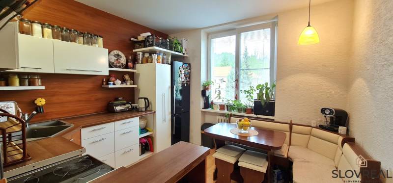 A kitchen in a 2-room apartment with a stove, refrigerator, and seating. Lots of natural light.