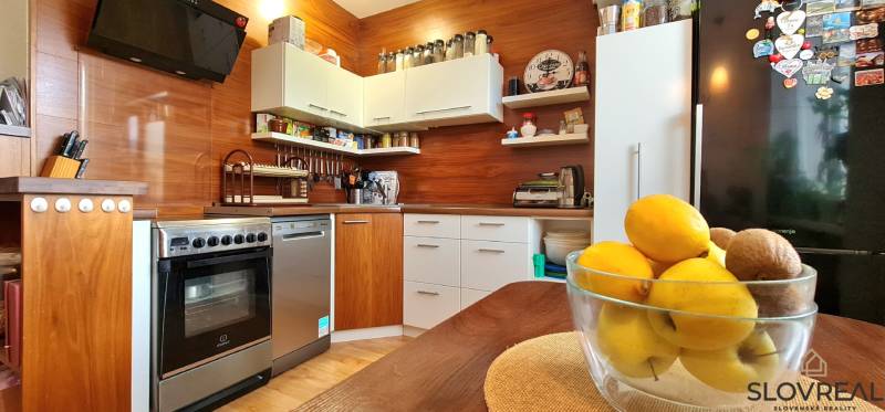 A kitchen in a 2-room apartment with a wood-patterned floor and fruit on the table.