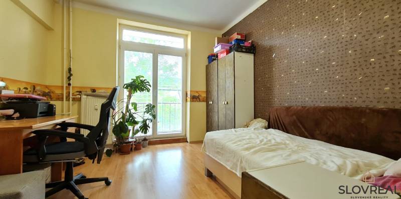 A simple room with a wooden floor and a desk in a two-room apartment.