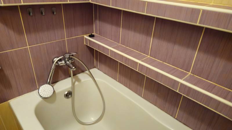A bathroom with colorful tiles and a bathtub in a 2-room apartment.
