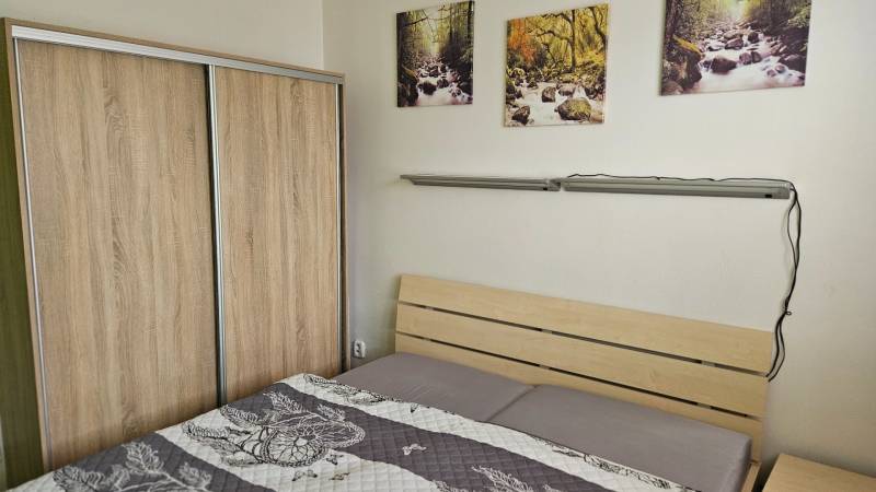 Bedroom in a 2-room apartment with a bed and a wardrobe with a wooden decor.