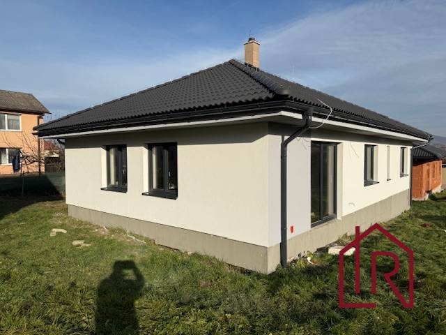 A family house in Bretejovce with a dark roof and a white facade, surrounded by a lawn.