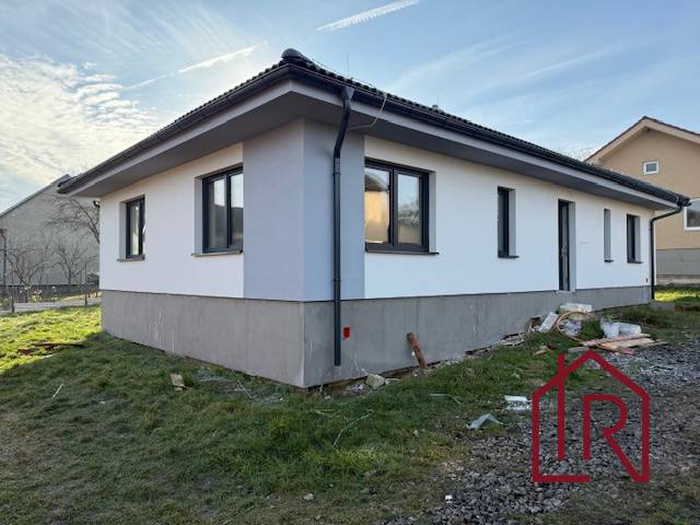 A family house in Bretejovce with white plaster, black windows, and a gable roof.