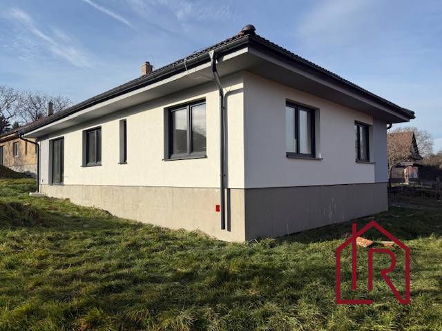 A family house in Bretejovce with a light facade and a dark roof, surrounded by greenery.