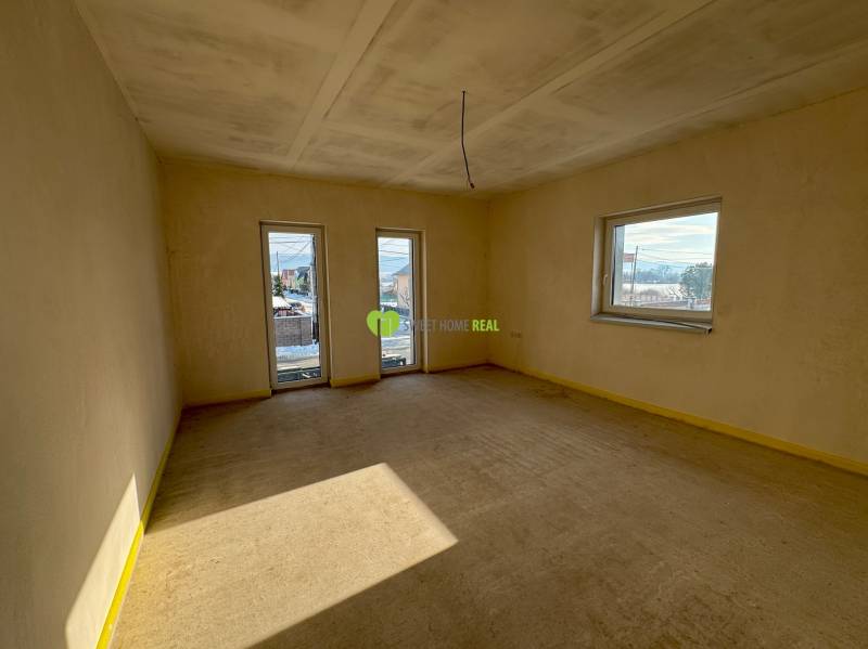 Spacious room with large windows in a family house, allowing a view of the surroundings.
