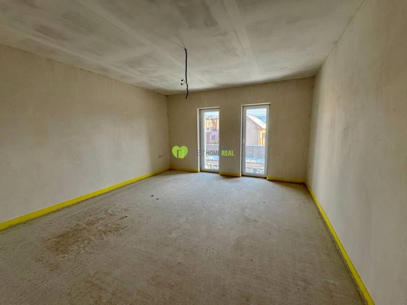 Empty room in a family house with two French windows and smooth walls.