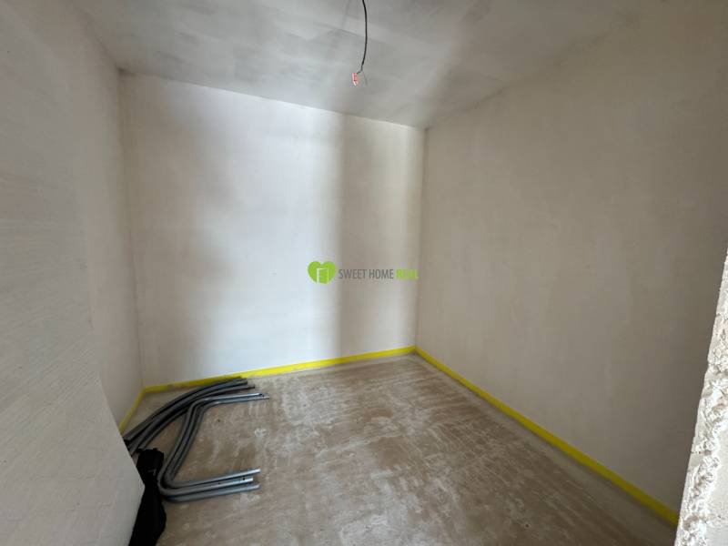 Unfinished room in a family house with wires on the floor and raw walls.