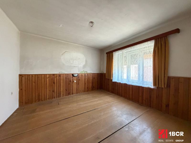 Family house with wood-patterned flooring, wall cladding, large window with lace curtains.