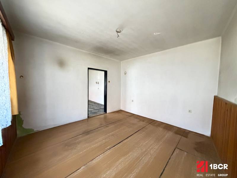 A place in a family house with a wooden decor floor, white walls, and open doors.