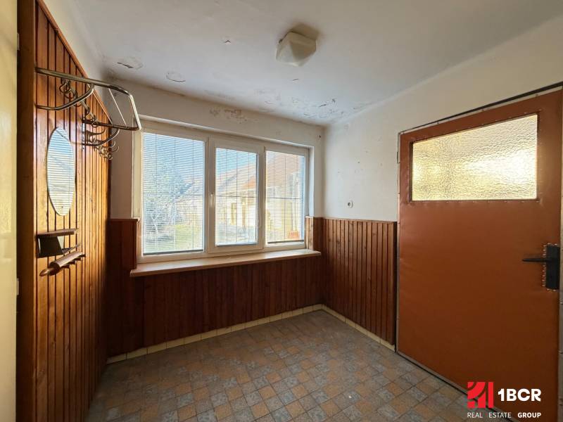 The interior of a family house with paneling, large windows, and a wall-mounted coat rack.