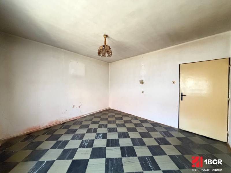 A room in a family house with a checkered floor and austere lighting.