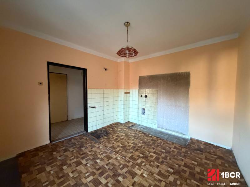 Interior of a family house with a wooden decor floor and a tiled wall ready for installation.