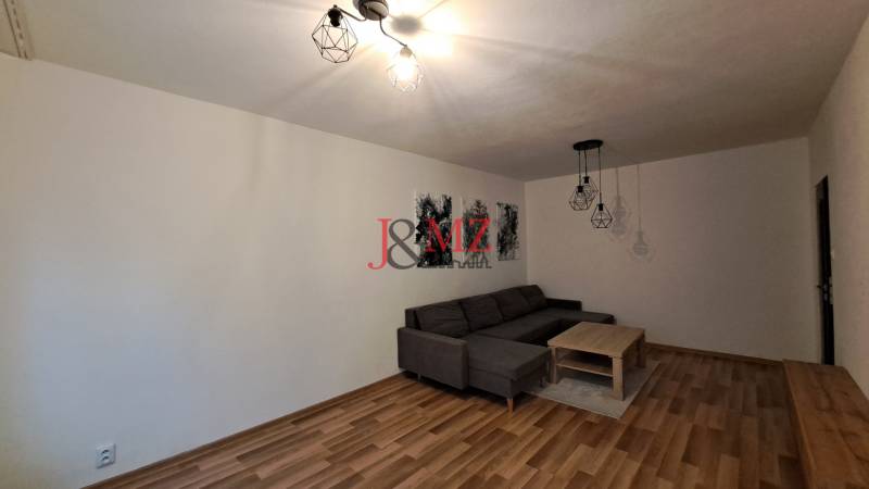 Living room in a two-room apartment with a sofa, coffee table, and floor lighting.