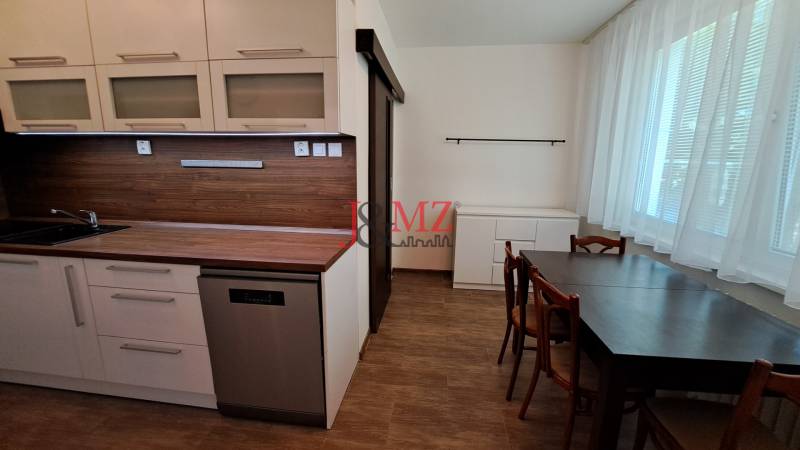 A kitchen in a 2-room apartment with wooden paneling and a dining table.