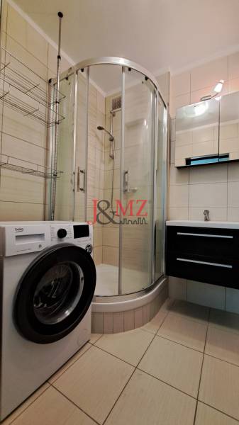 Bathroom in a 2-room apartment with a shower, sink, and washing machine.